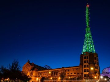 Alexandra Palace at night with the mast lit up in green.